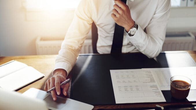 dreamstime_s_61655427 Business man working at office with laptop and documents on his desk