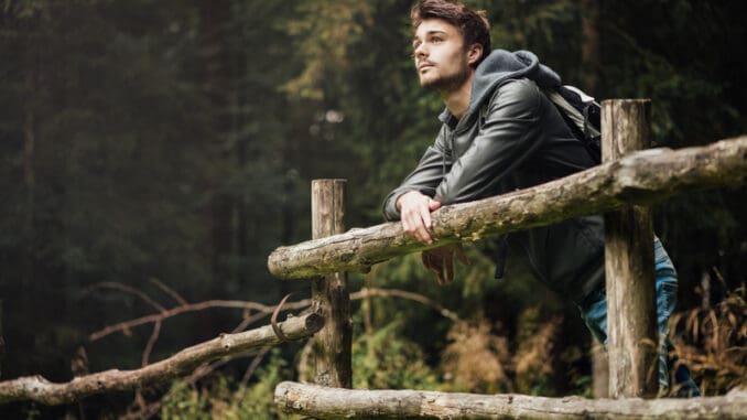 Young man with backpack hiking in the forest