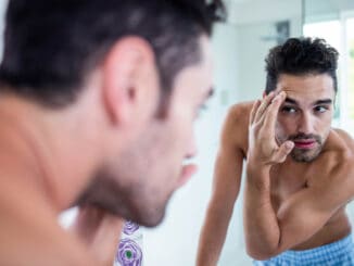 Handsome man looking at his hair in bathroom