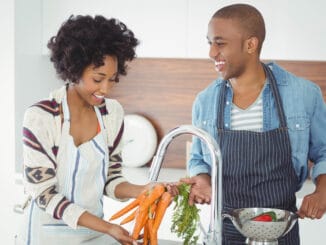 Happy couple washing vegetables in the kitchen