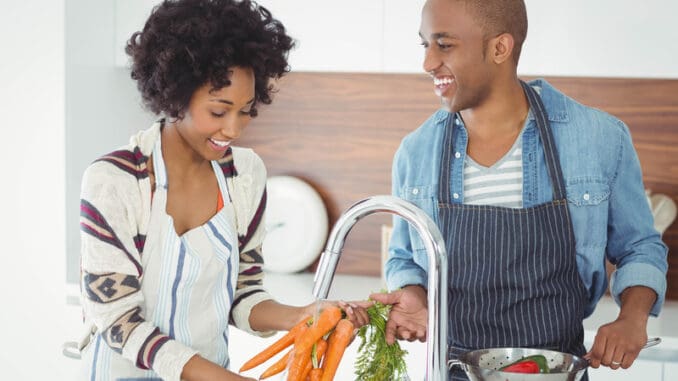 Happy couple washing vegetables in the kitchen