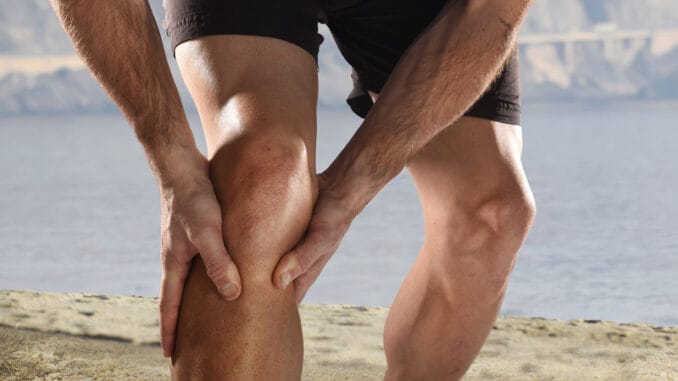 dreamstime_s_66973563 Young sport man with strong athletic legs holding knee with his hands in pain