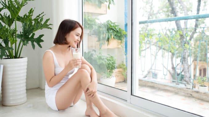 Asian beautiful young woman drinking milk at home.