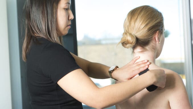 A Physiotherapist applying kinesiology tape for painful shoulder