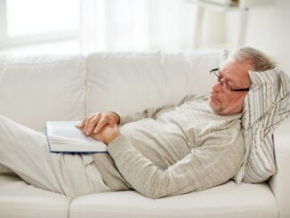 Old age, rest and people concept - senior man lying on sofa with book and sleeping at home