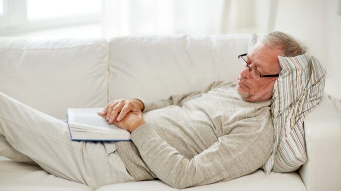 Old age, rest and people concept - senior man lying on sofa with book and sleeping at home