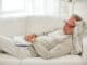 Old age, rest and people concept - senior man lying on sofa with book and sleeping at home