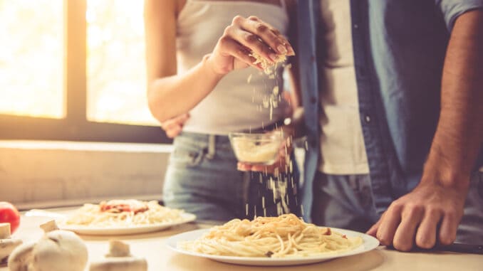 dreamstime_s_79073656 Woman is adding grated cheese