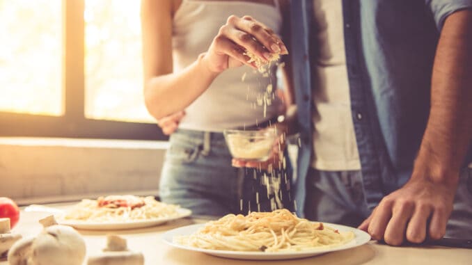 Woman is adding grated cheese