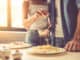 Woman is adding grated cheese