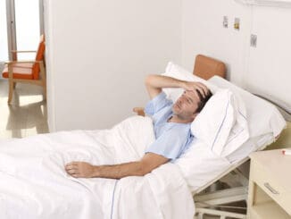 Young patient man lying at hospital bed resting tired looking sad and depressed