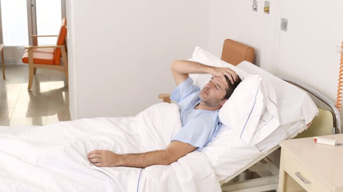 Young patient man lying at hospital bed resting tired looking sad and depressed