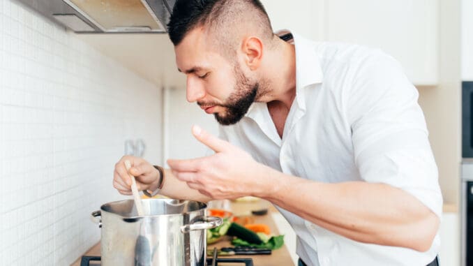 Modern lifestyle with man cooking soup and preparing dinner.