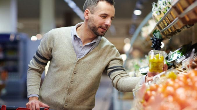 Portrait of smiling handsome man grocery shopping in supermarket