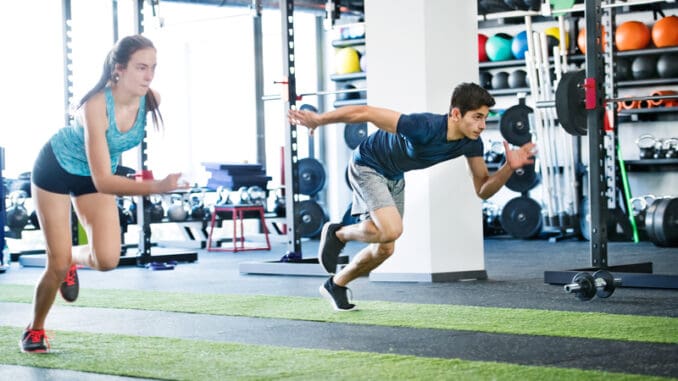 Young fit couple in gym fast running.