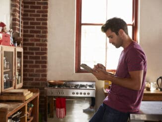 Young man using tablet computer in kitchen, waist up