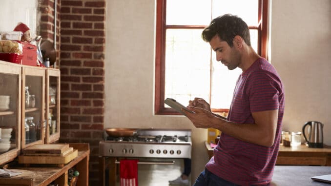 Young man using tablet computer in kitchen, waist up