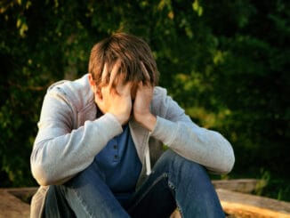 Sad Young Man sit on the Bench outdoor