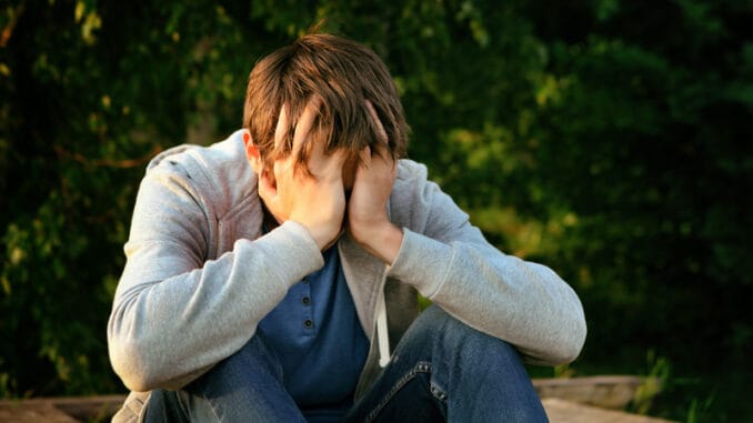 Sad Young Man sit on the Bench outdoor