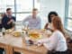 Business colleagues discussing while sitting around breakfast table at office cafeteria