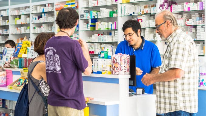 young pharmacist helping customers at the counter