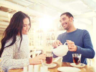 happy couple drinking tea at cafe or restaurant