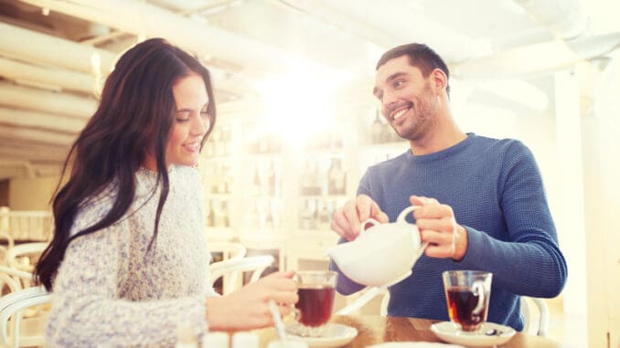 happy couple drinking tea at cafe or restaurant